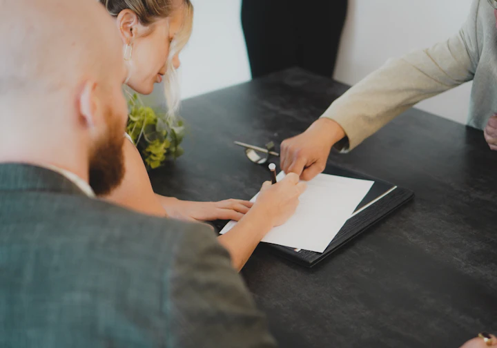 Casal assinando documento com orientação na mesa
