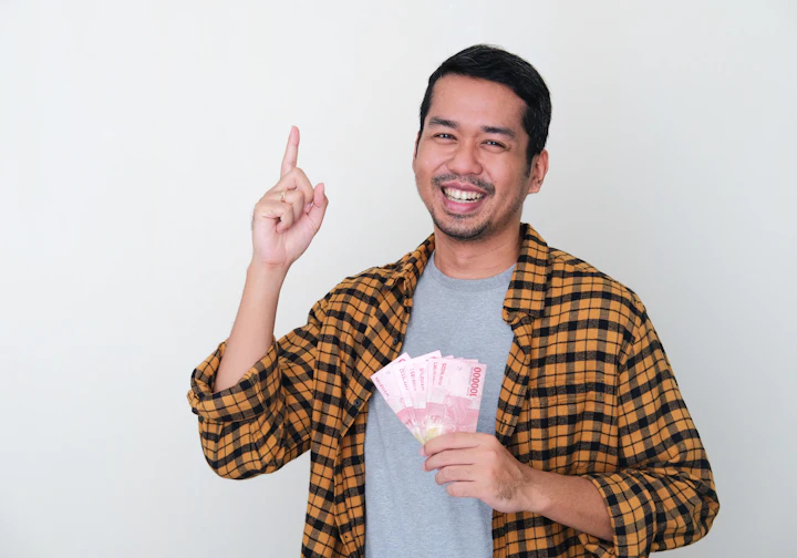 Jovem sorrindo com dinheiro na mão