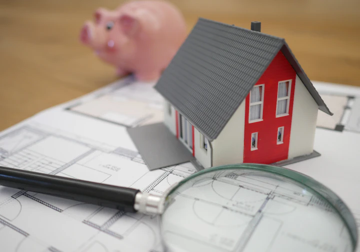 Miniatura de casa sobre a planta, com lupa