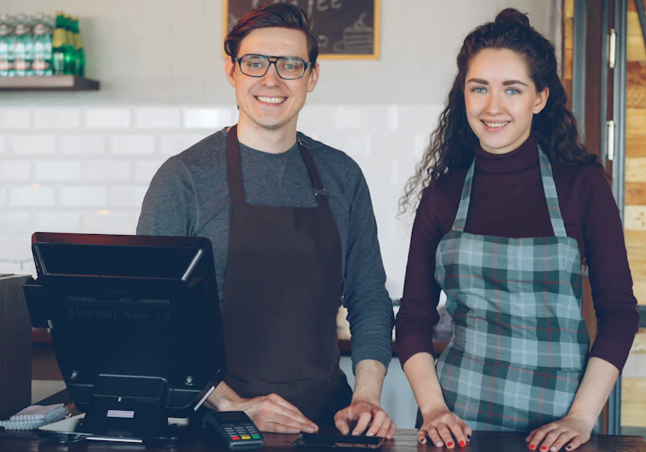 Donos de um café sorrindo atrás do balcão