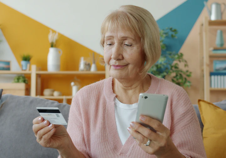 Aposentada segurando o cartão e o celular