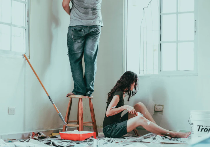 Casal pintando a parede na reforma da casa