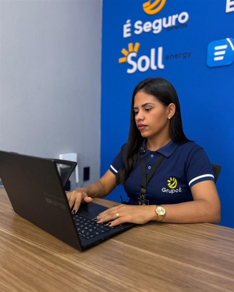 Colaboradora do Grupo É, de uniforme, atendendo no escritório da unidade