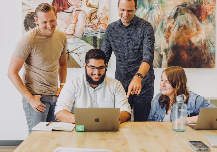 Pequena equipe sorrindo em volta do notebook